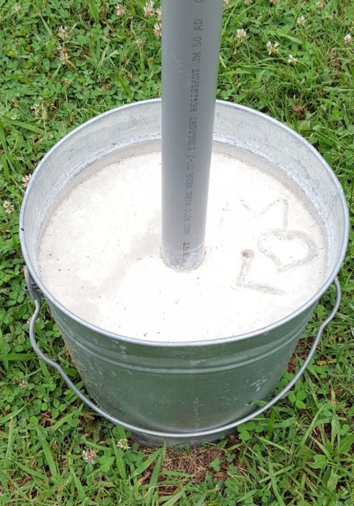 a metal bucket sitting in the grass with a pole sticking out of it's side