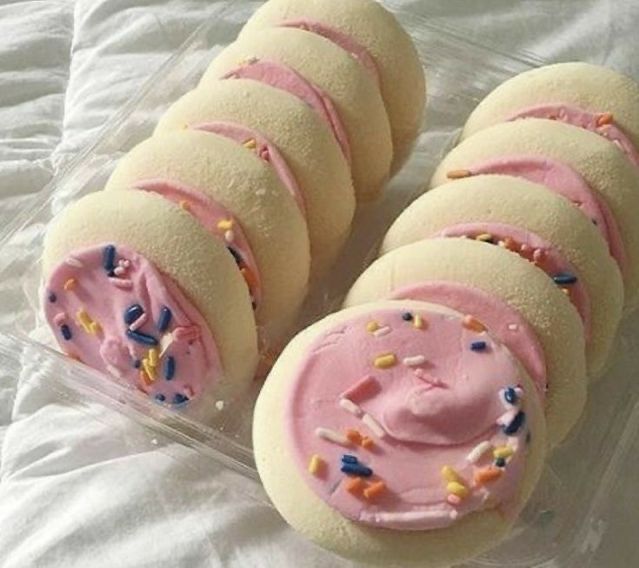 there are six cookies with pink frosting and sprinkles on them in a plastic container