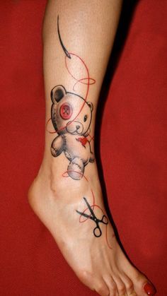 a person with a tattoo on their foot has scissors and a teddy bear in it