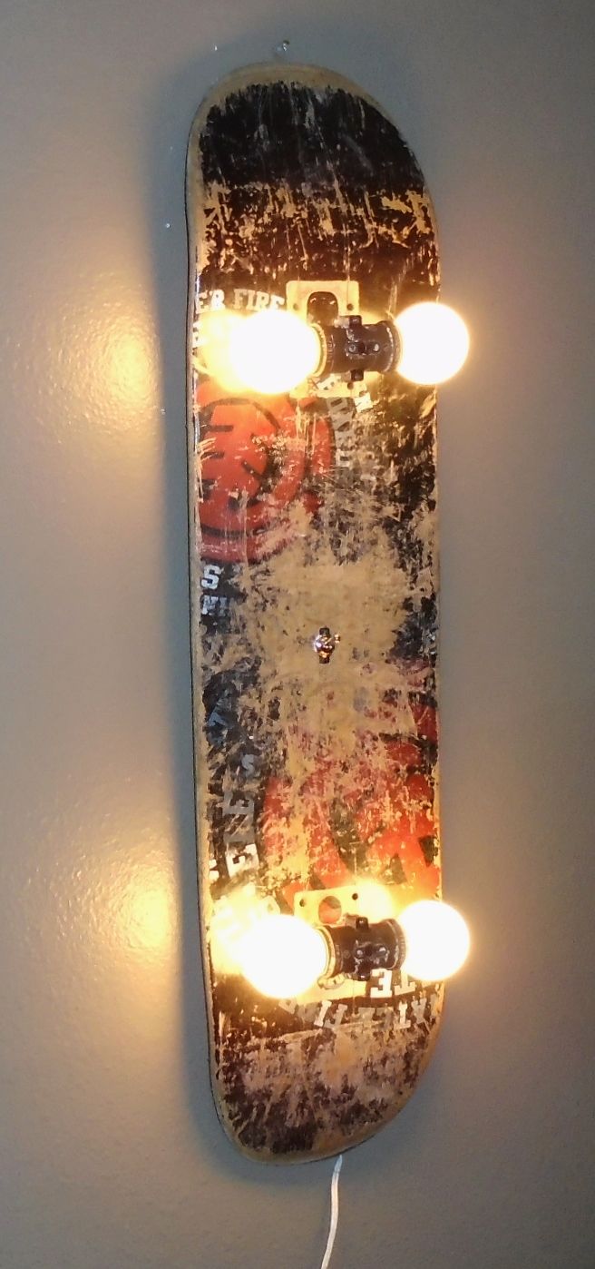 a skateboard with lights attached to the side of it hanging on a white wall