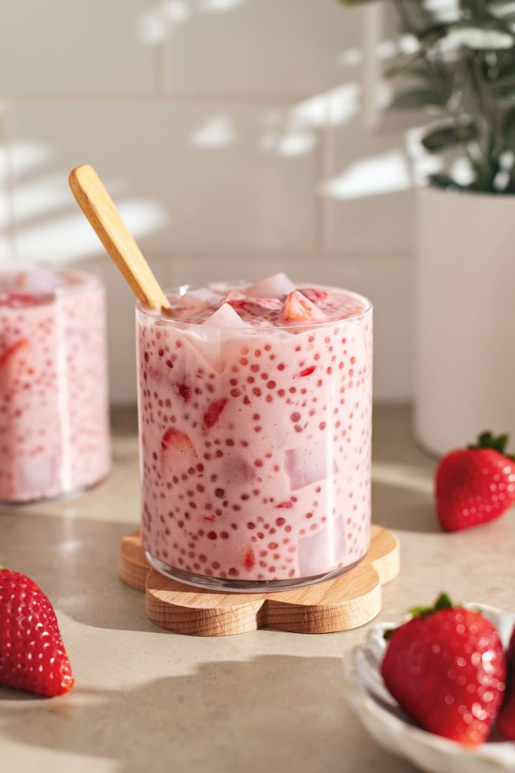 two glasses with strawberries in them on a table