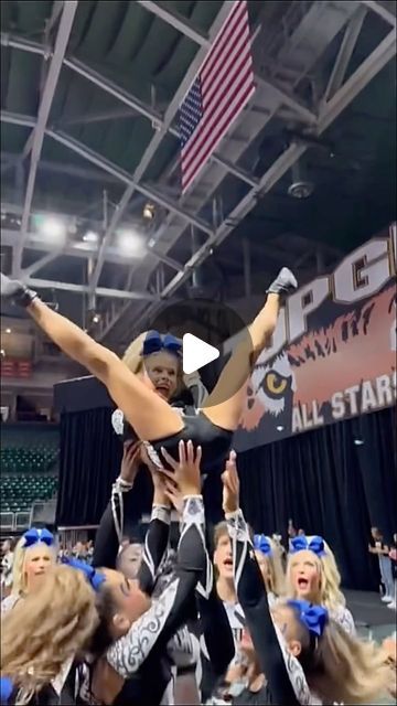 the cheerleaders are all dressed in black and white, while one girl is holding up her arms