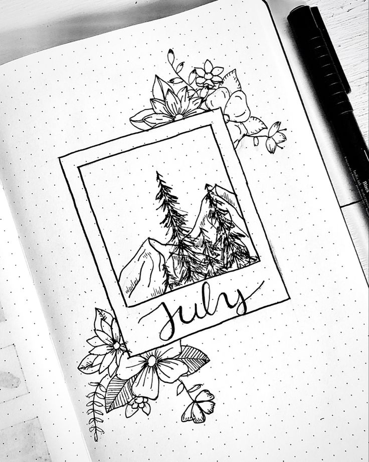 an open notebook with the word july written on it and some flowers in front of it