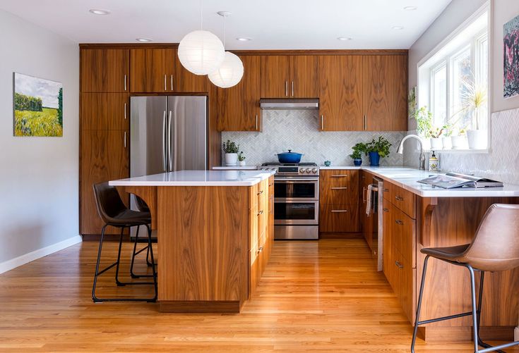 a kitchen with wooden cabinets and stainless steel appliances, along with two bar stools