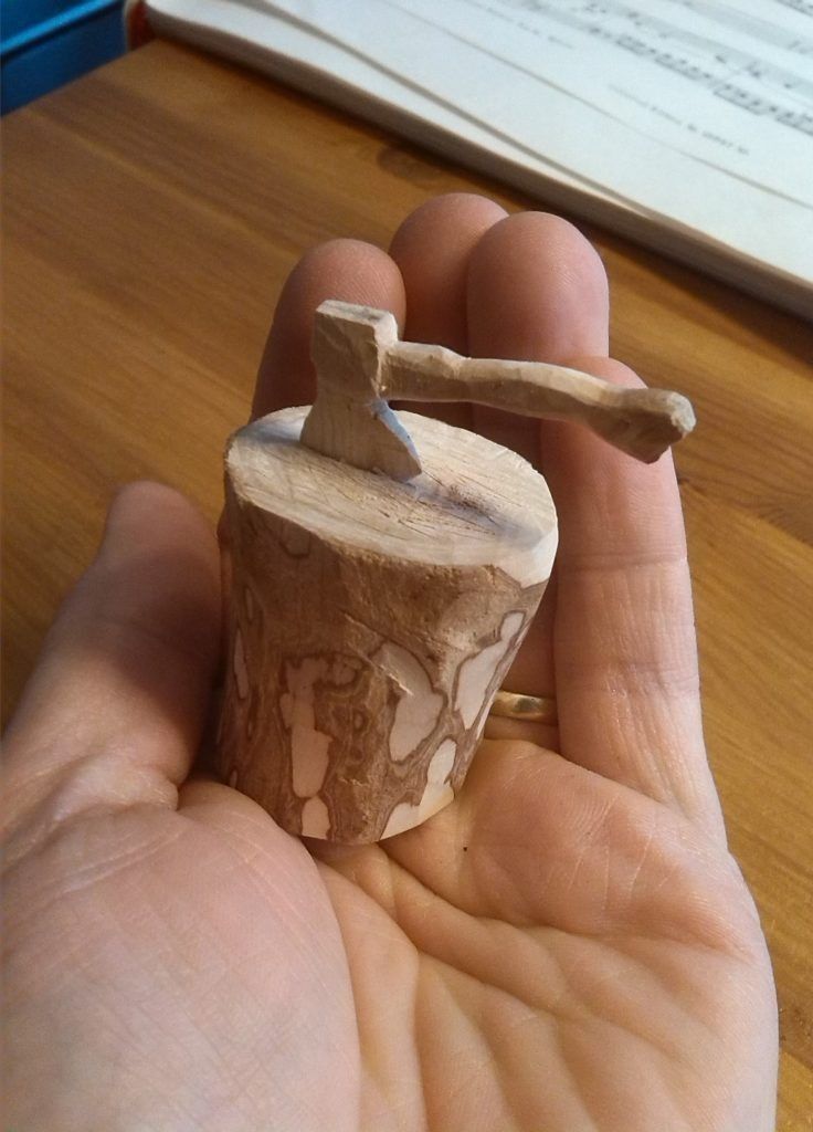 a person holding a small piece of wood in their hand with an hammer stuck into it