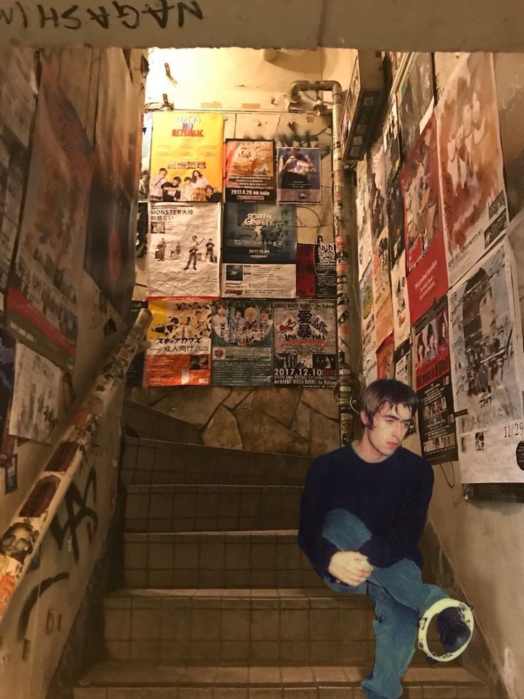 a young man sitting on the stairs in an alley