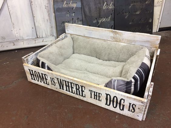 a dog bed in a wooden crate with the words home is where the dog is