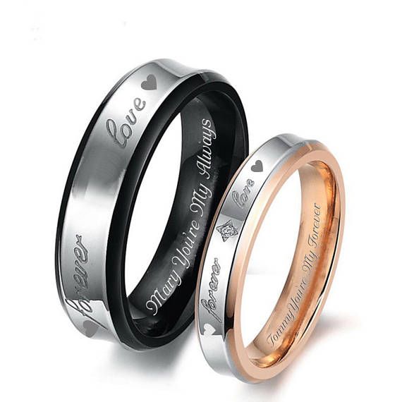 two wedding rings with hearts engraved on the side and one has an inscription in it