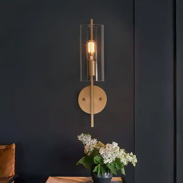 a vase with flowers on a table next to a wall light