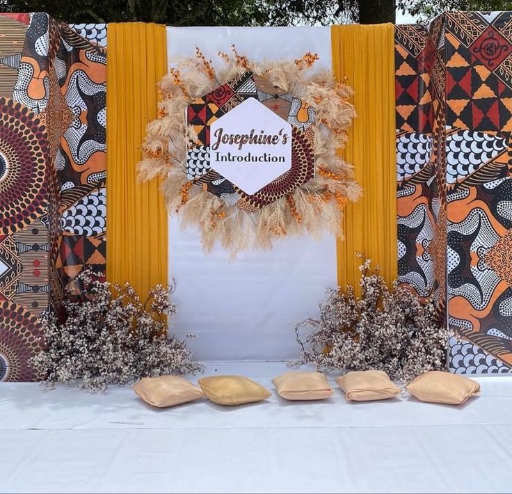 a table topped with an orange and yellow decorated wall next to wooden spoons on top of a white cloth covered table