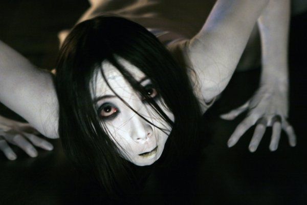 a woman with long black hair and white makeup is posing for the camera while holding her hands behind her head