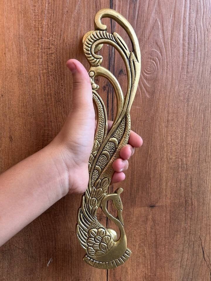 a hand holding an ornate brass door handle