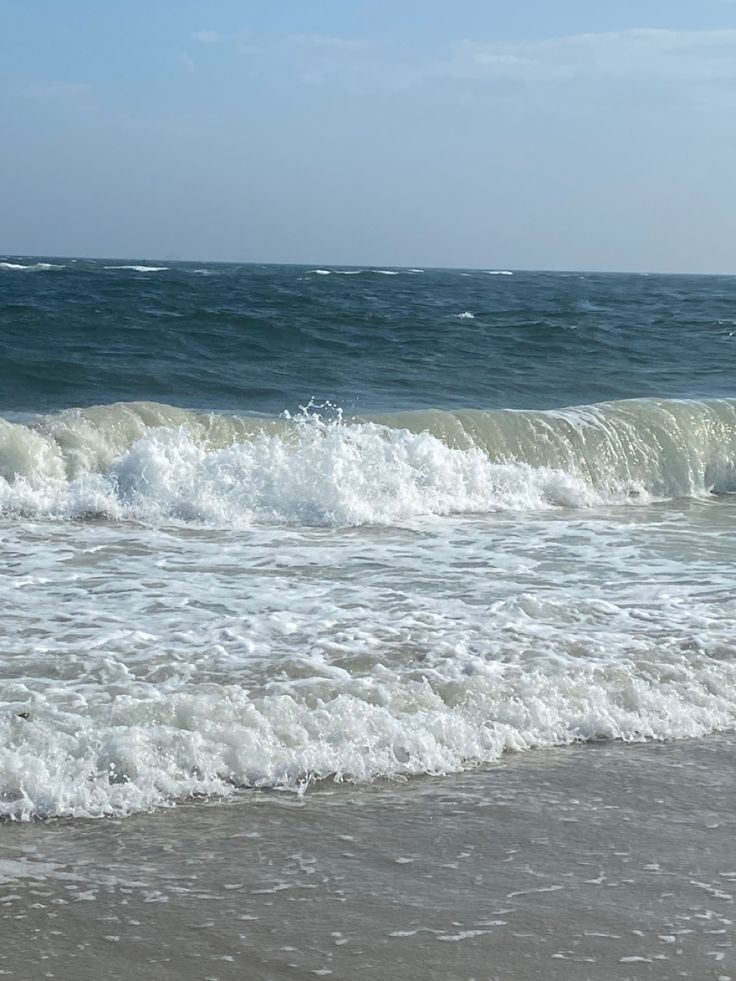 a person riding a surfboard on top of a wave in the ocean near shore