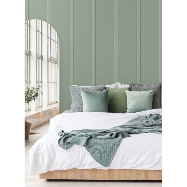 a bedroom with green walls and white bedding, along with pillows on the headboard