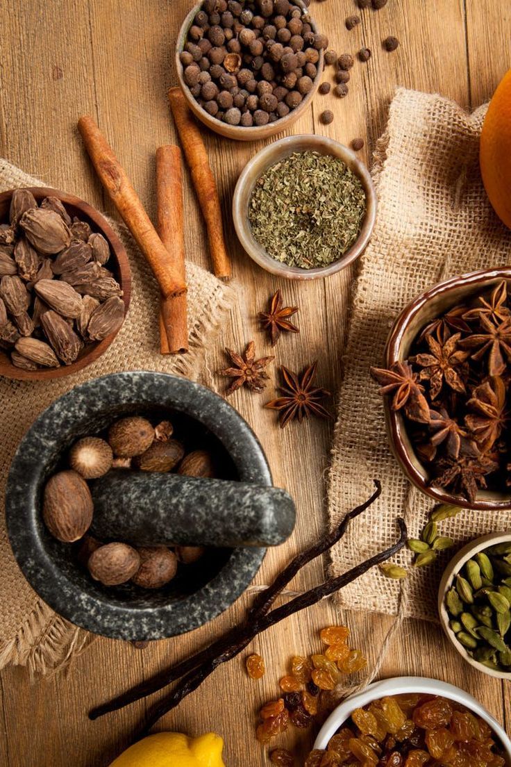 an assortment of spices and nuts on a wooden table next to oranges, cinnamons, cloves