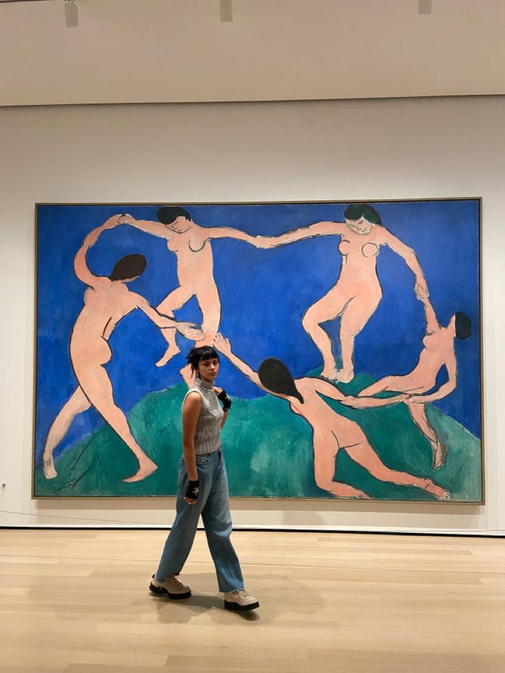 a woman is walking in front of a painting