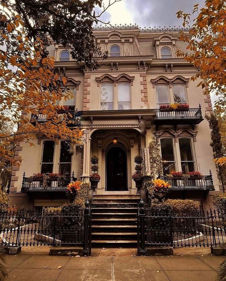 an old house with many windows and balconies on the front porch, surrounded by autumn foliage