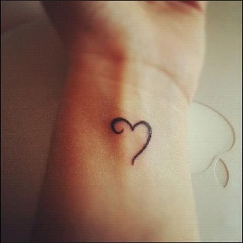 a small heart tattoo on the wrist