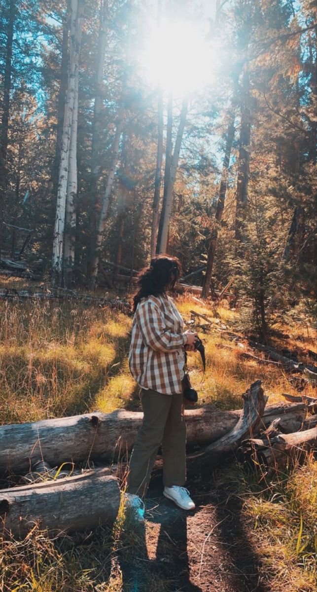 a woman standing on a log in the woods