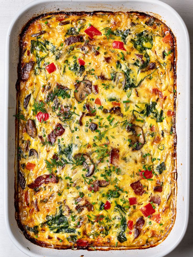 a casserole dish with vegetables and cheese in it on a white table top