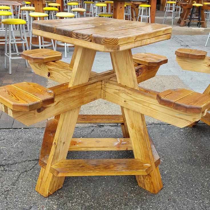 a picnic table made out of wooden planks in an outdoor setting with yellow chairs