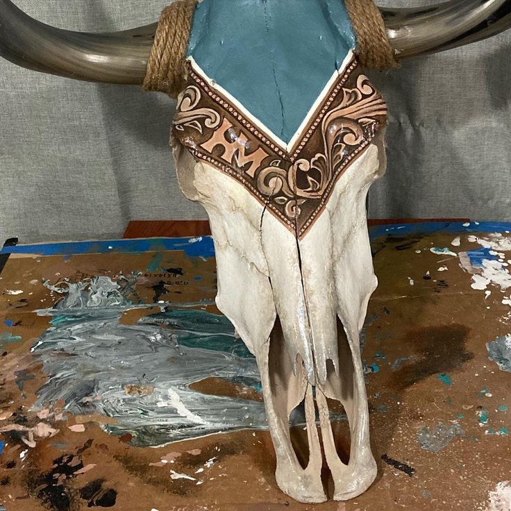 a cow skull with a blue bandanna around it's neck sitting on a table