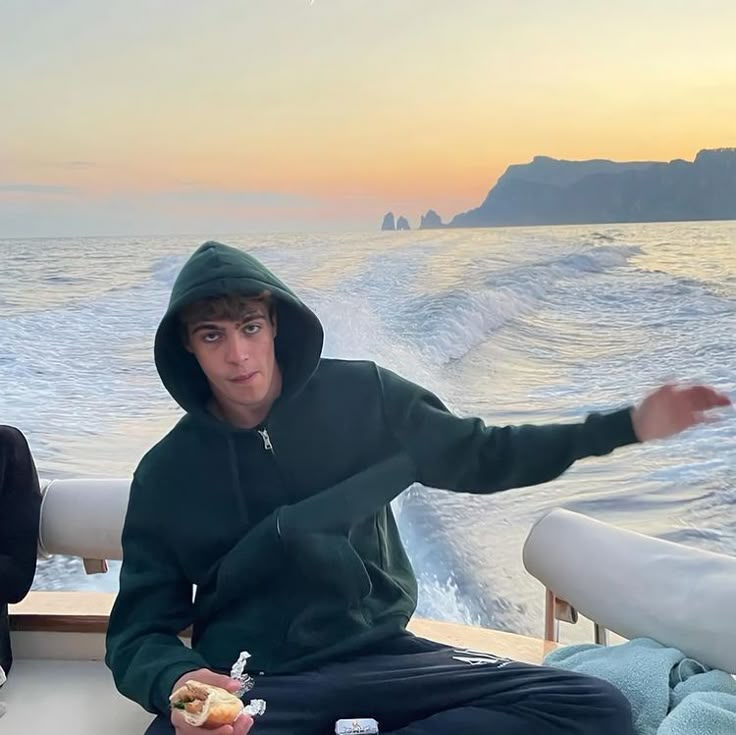 two people sitting on the back of a boat in the ocean eating food and drinking