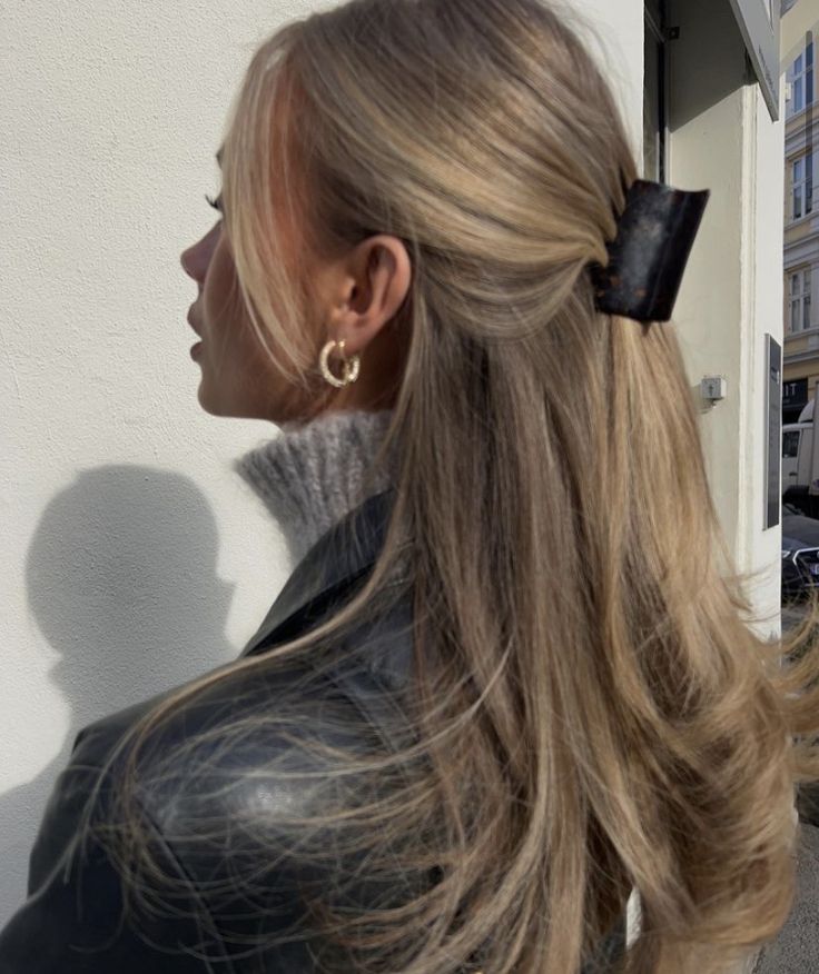 a woman with long blonde hair wearing a black leather jacket and large gold hoop earrings