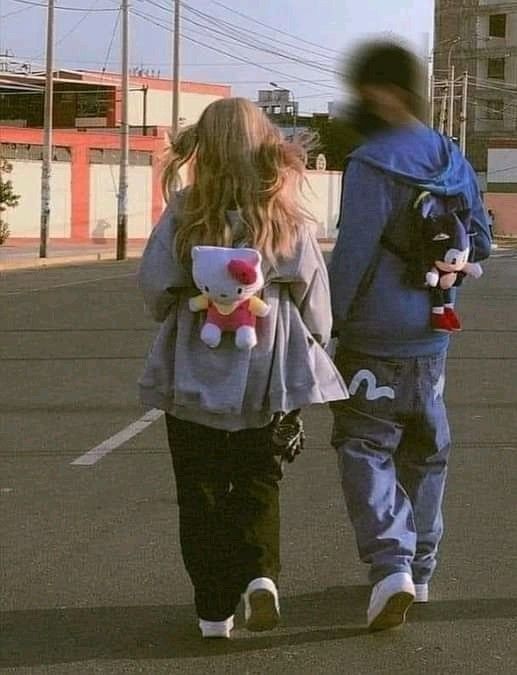 two people walking down the street with stuffed animals