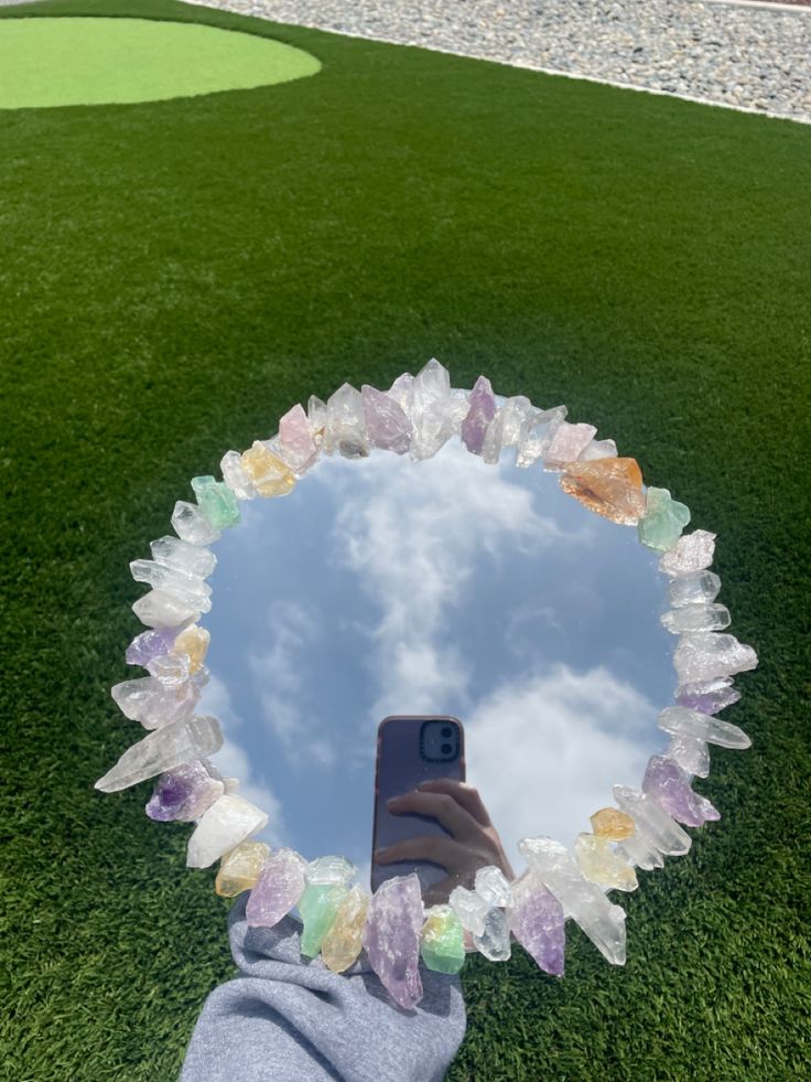 a person taking a selfie with their cell phone in front of a circular mirror