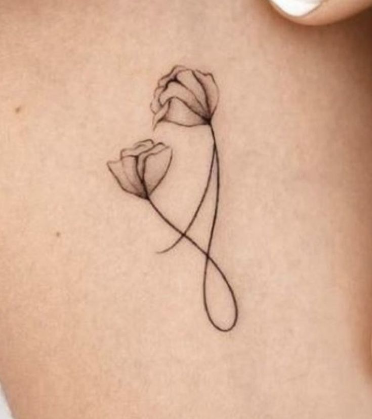 a woman's stomach with a flower tattoo on the side of her back shoulder