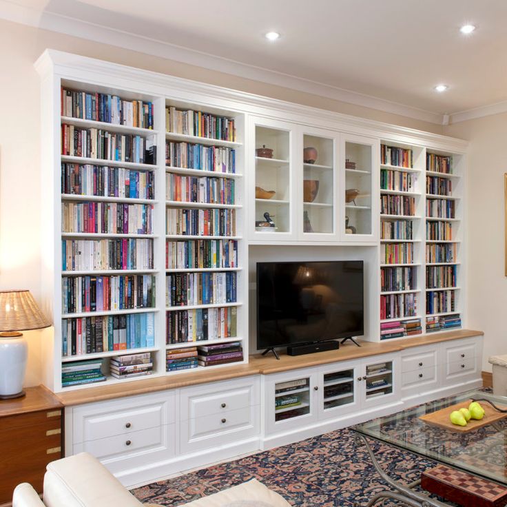 a living room filled with furniture and a flat screen tv sitting on top of a book shelf