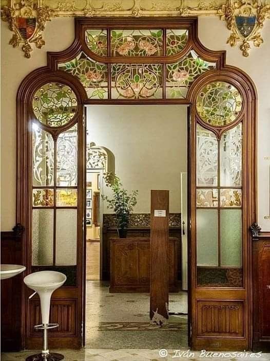 an ornate doorway leading into a room with wooden doors and glass panels on the walls