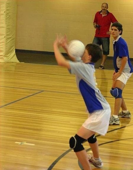 young boys playing volleyball in an indoor gym