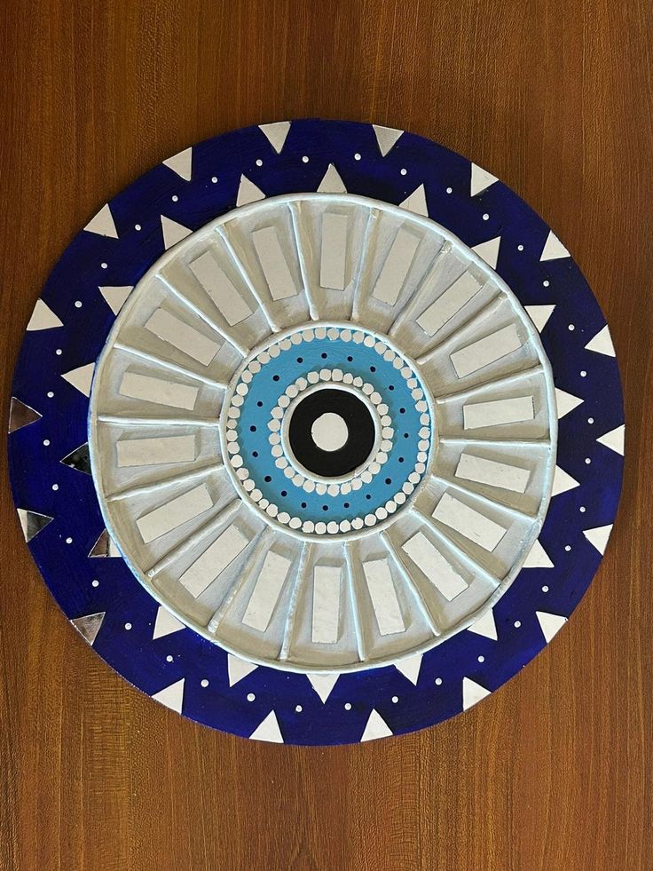 a blue and white plate with an eye on it sitting on a wooden table top