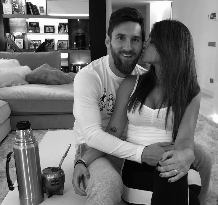 a man and woman sitting next to each other in front of a coffee table with a water bottle on it