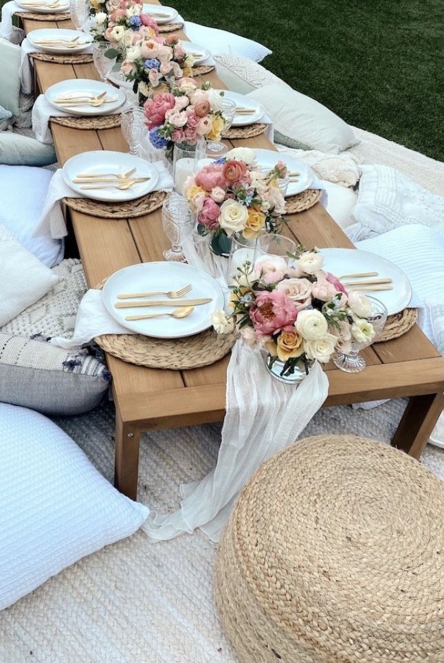 a long table set up with plates and place settings for an outdoor dinner or bridal party