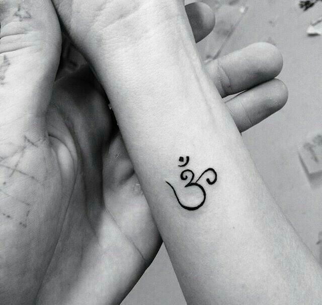 two hands holding each other with a tattoo on their wrist that has an om symbol