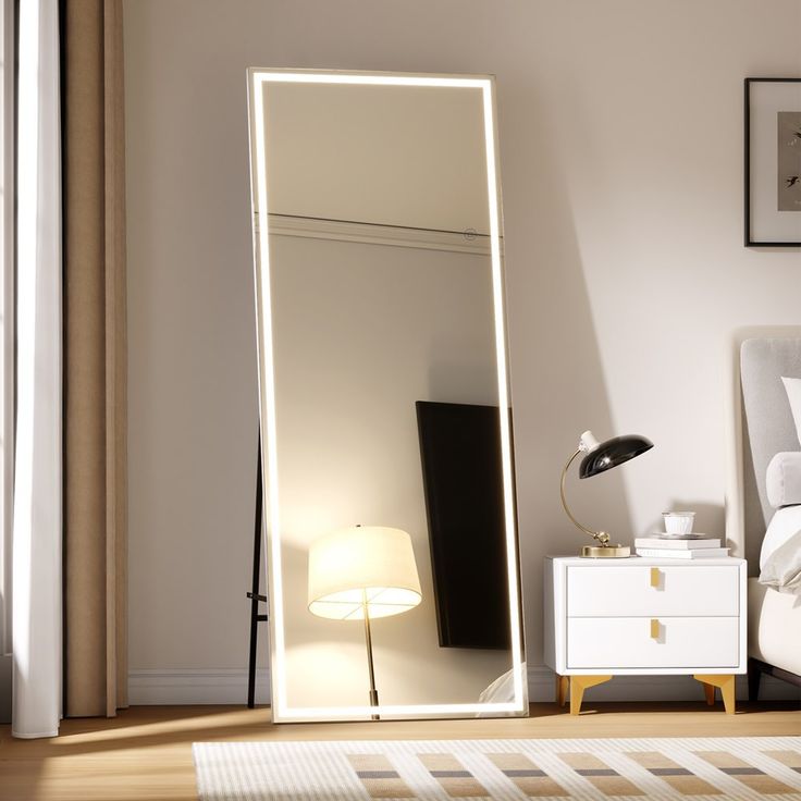 a white bed room with a large mirror on the wall and a lamp next to it