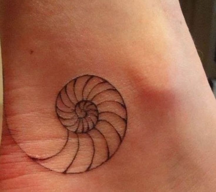 a small tattoo on the ankle of a woman's foot with a spiral design