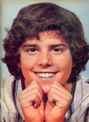 an old photo of a young boy with his hands on his chin and smiling at the camera