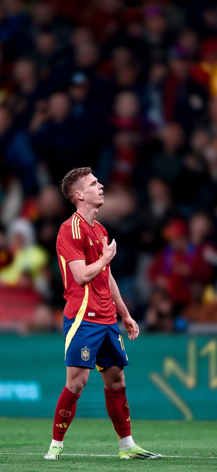 a man standing on top of a soccer field holding his hands together while looking up