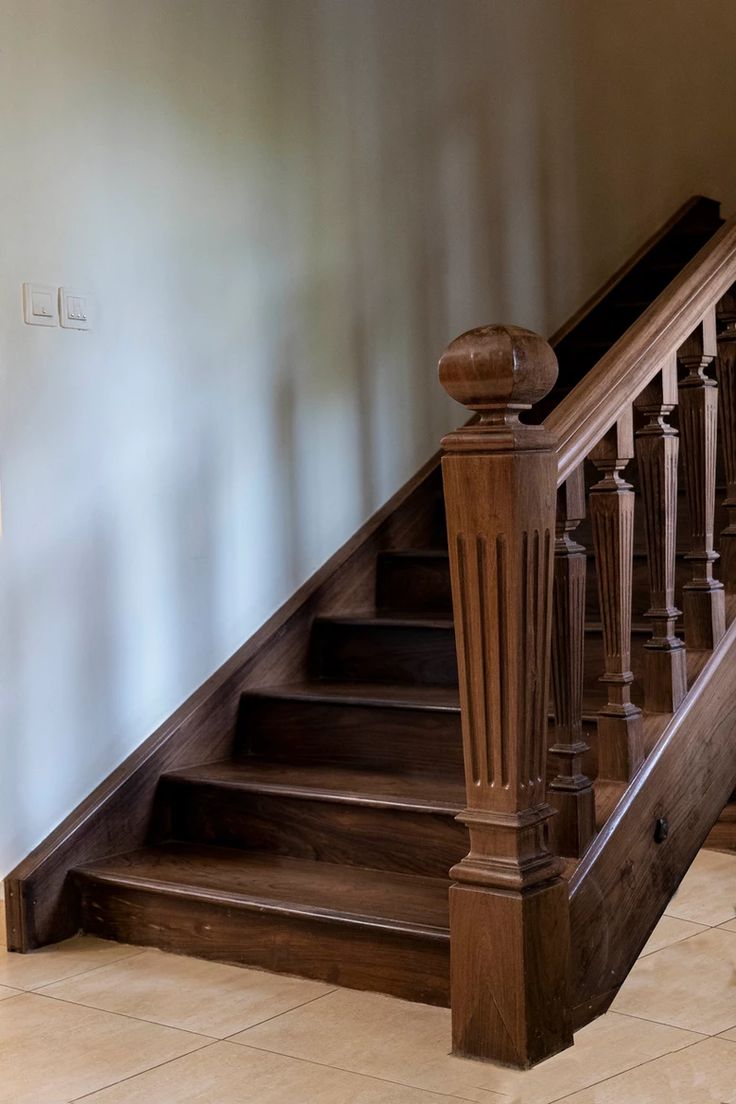 a wooden stair case next to a tiled floor