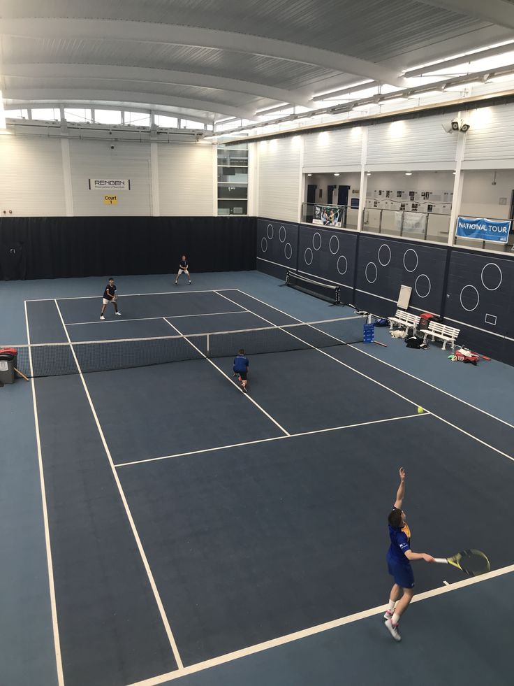 people are playing tennis on an indoor court