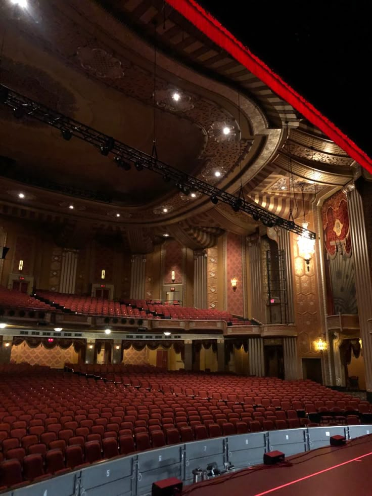 an empty auditorium with red seats and chandelier