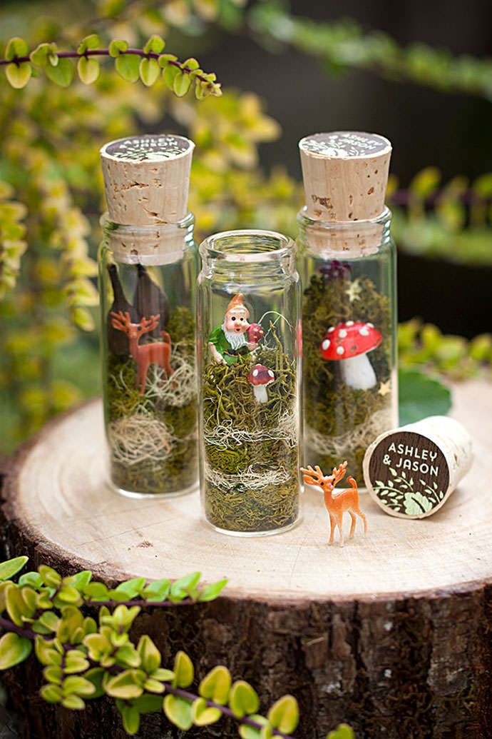 three glass bottles filled with plants sitting on top of a tree stump