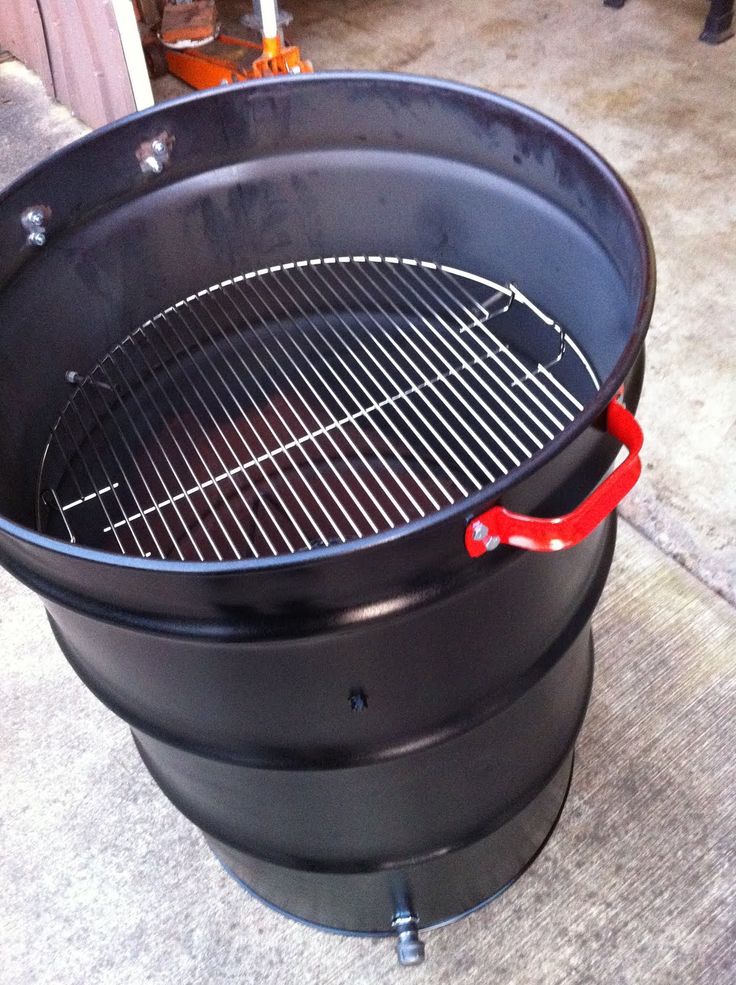 an outdoor bbq grill on the ground with tongs sticking out of it's side