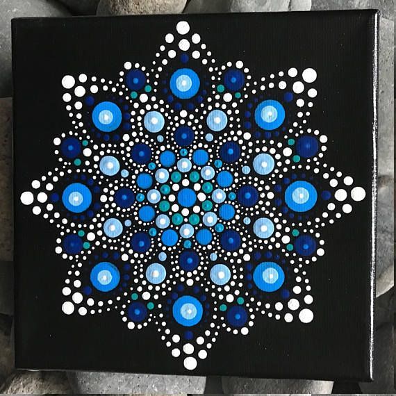 a black and white painting with blue dots on it's center is surrounded by rocks