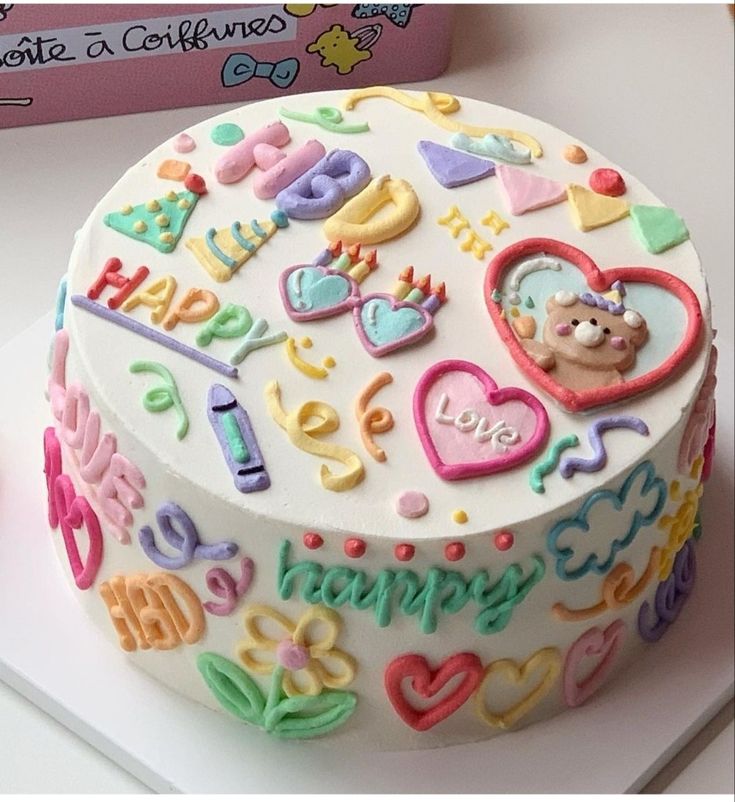 a birthday cake decorated with lots of colorful icing on top of a white table