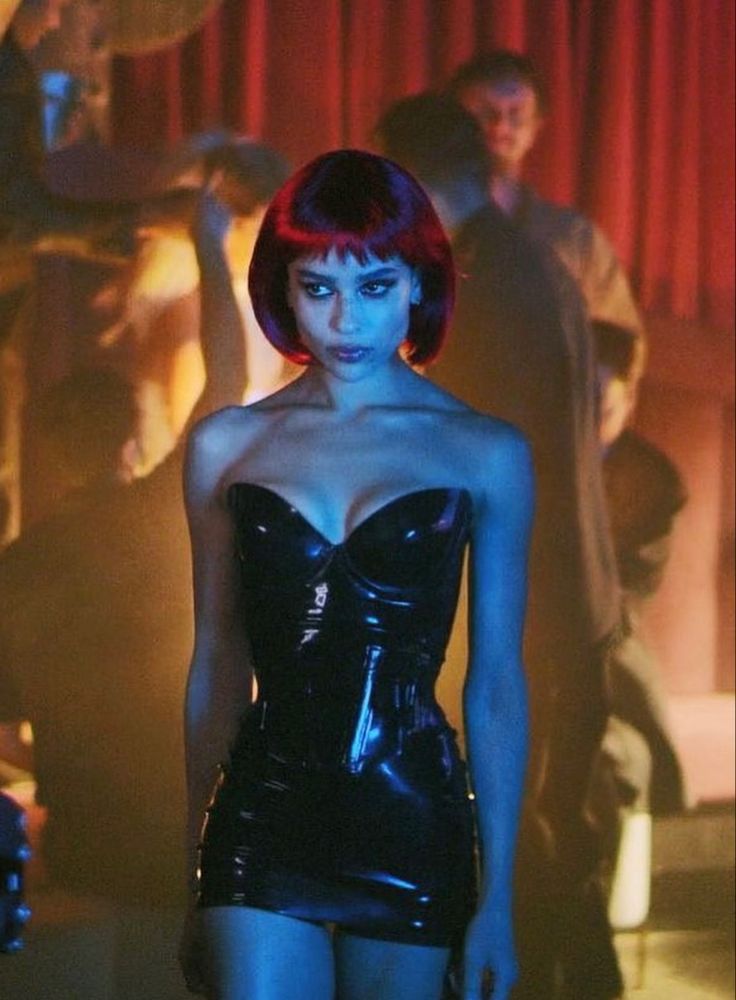 a woman with red hair and black latex is standing in front of a group of people